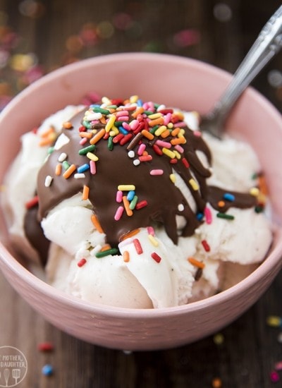 A bowl of vanilla ice cream topped with chocolate magic shell and sprinkles.