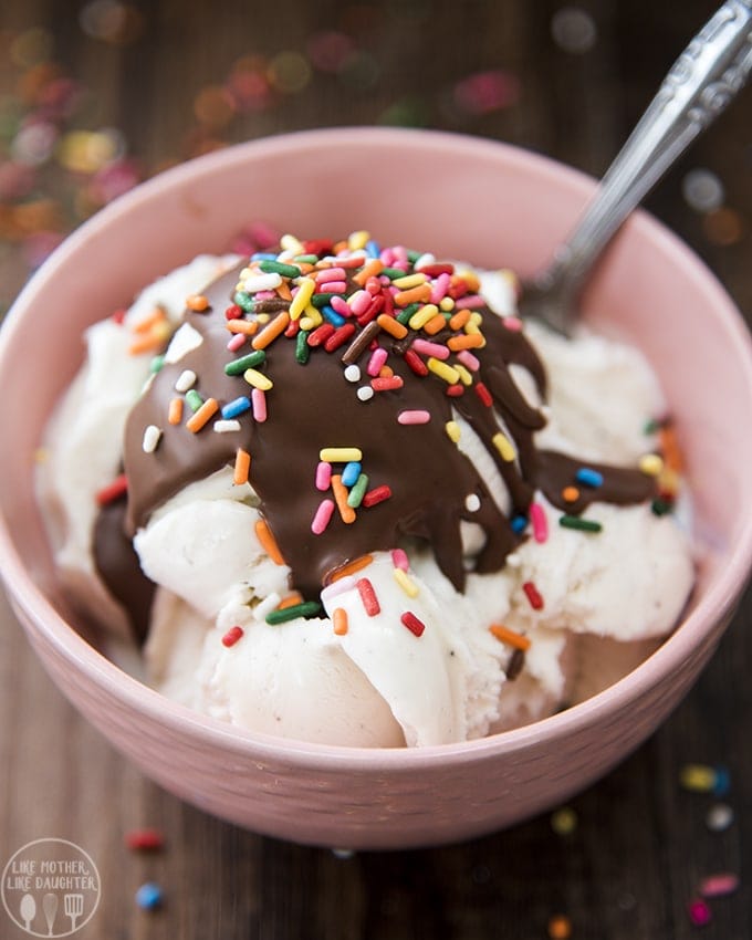 A bowl of vanilla ice cream topped with chocolate magic shell and sprinkles.