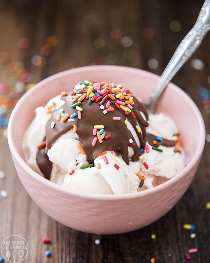 A pink bowl filled with vanilla ice cream, topped with chocolate magic shell. 