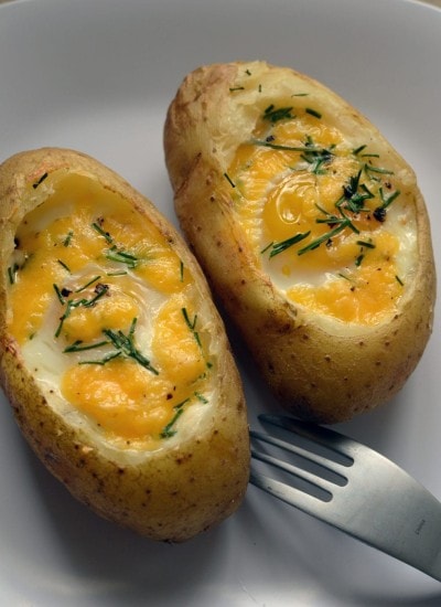 Top view of a baked egg in a baked potato on a white plate.