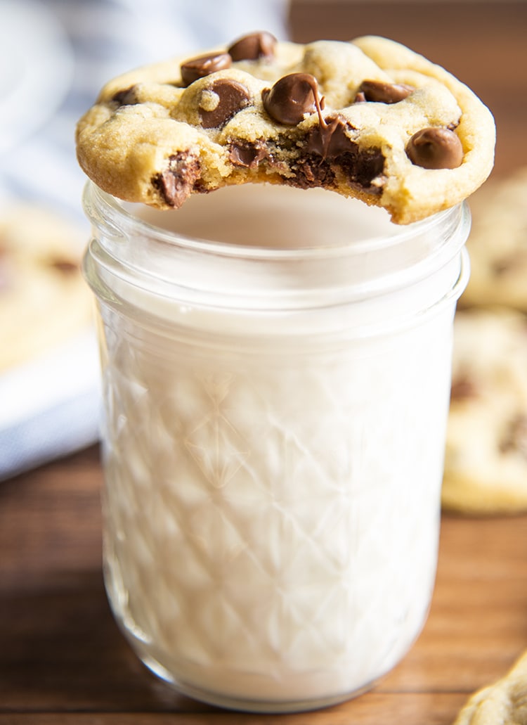 A chocolate chip cookie on a cup of milk