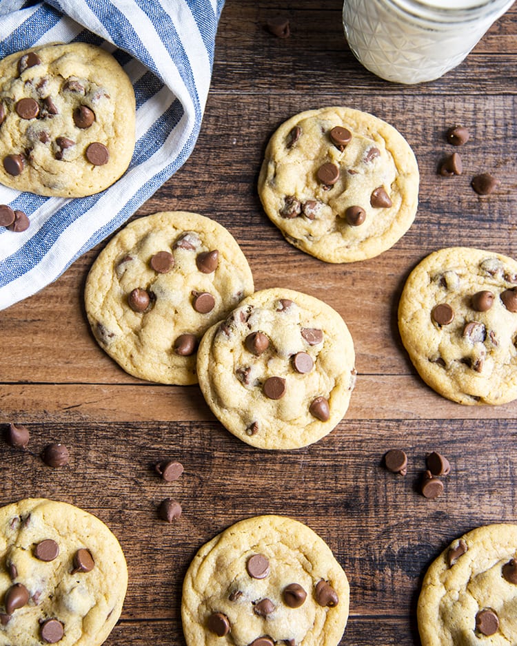 Chocolate Chip Pudding Cookies on a wooden background with chocolate chips around.