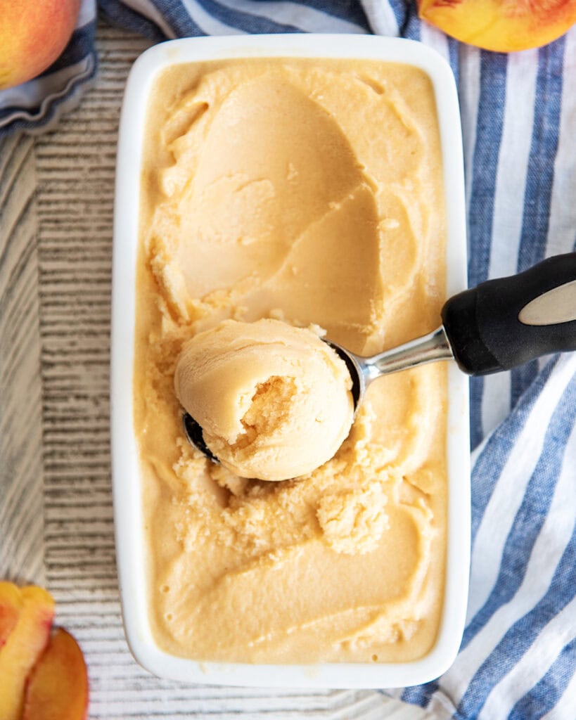 An above view of a container of ice cream, with 1 scoop on top.