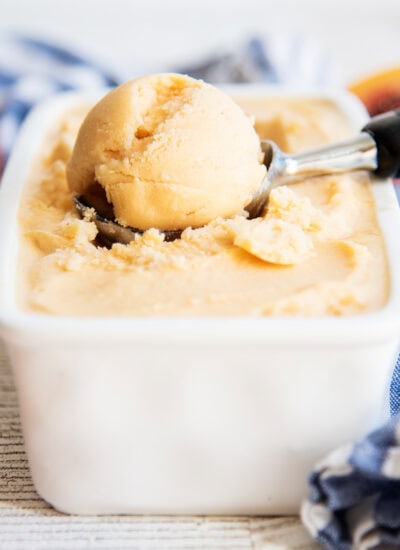 A scoop of an orange peach sherbet in an ice cream scoop.