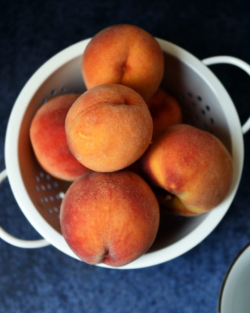 White strainer with fresh peaches 