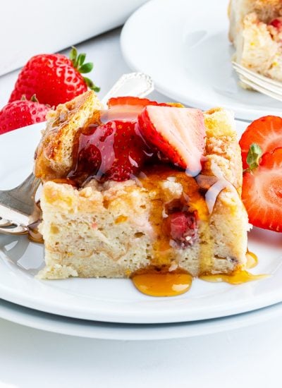 A piece of Baked strawberry French toast on a plate, topped with strawberries.