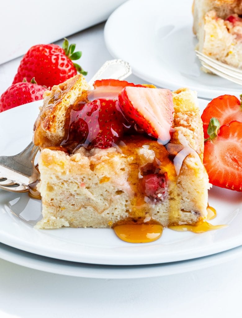 A piece of Baked strawberry French toast on a plate, topped with strawberries.
