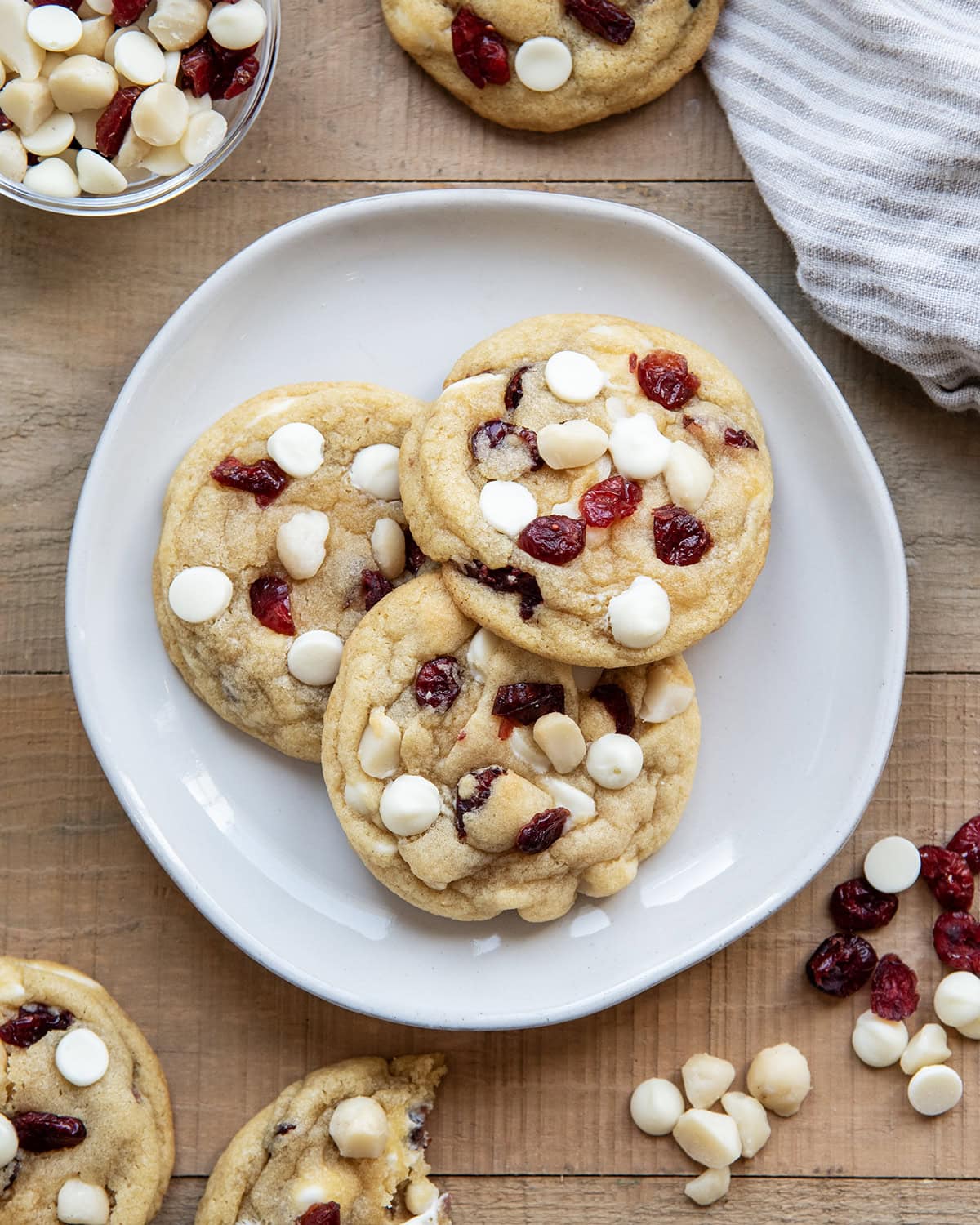 Three White Chocolate Cranberry Cookies with Macadamia Nuts on a plate next to a glass of milk.