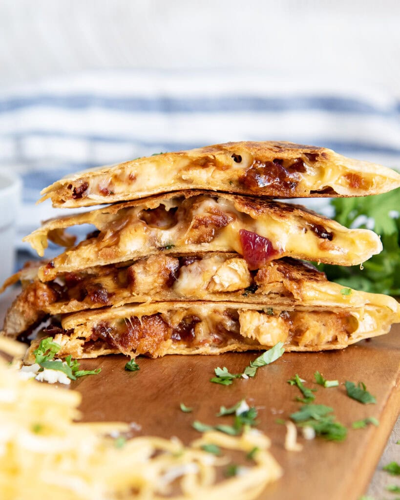 A stack of slices of BBQ Chicken Quesadilla on a wooden board.