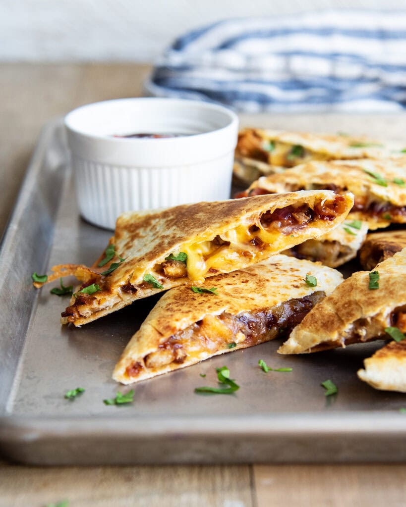 A stack of BBQ Chicken Quesadilla Slices on a metal baking pan. 