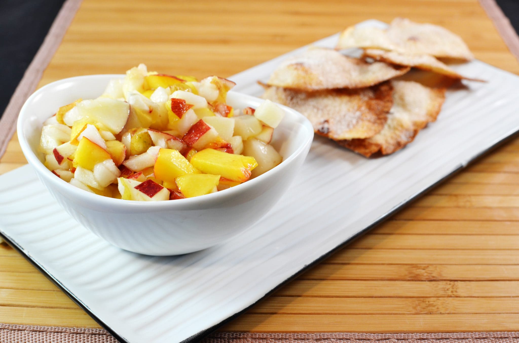 Angled view of fruit salsa with cinnamon chips in the background.