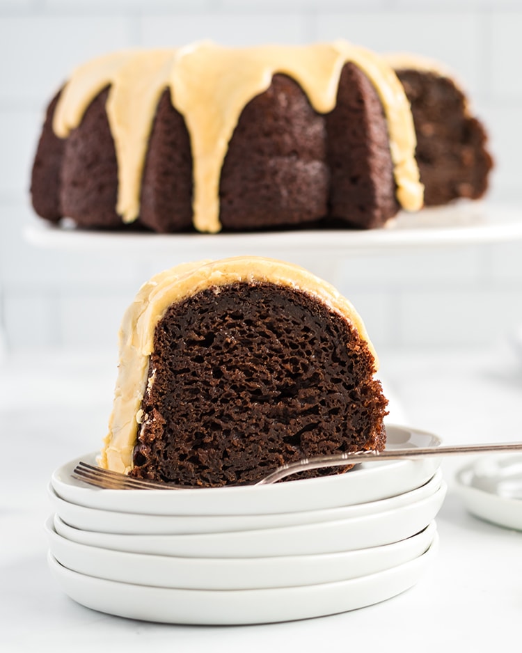 A slice of Chocolate Pumpkin Bundt Cake topped with a pumpkin icing on a plate.