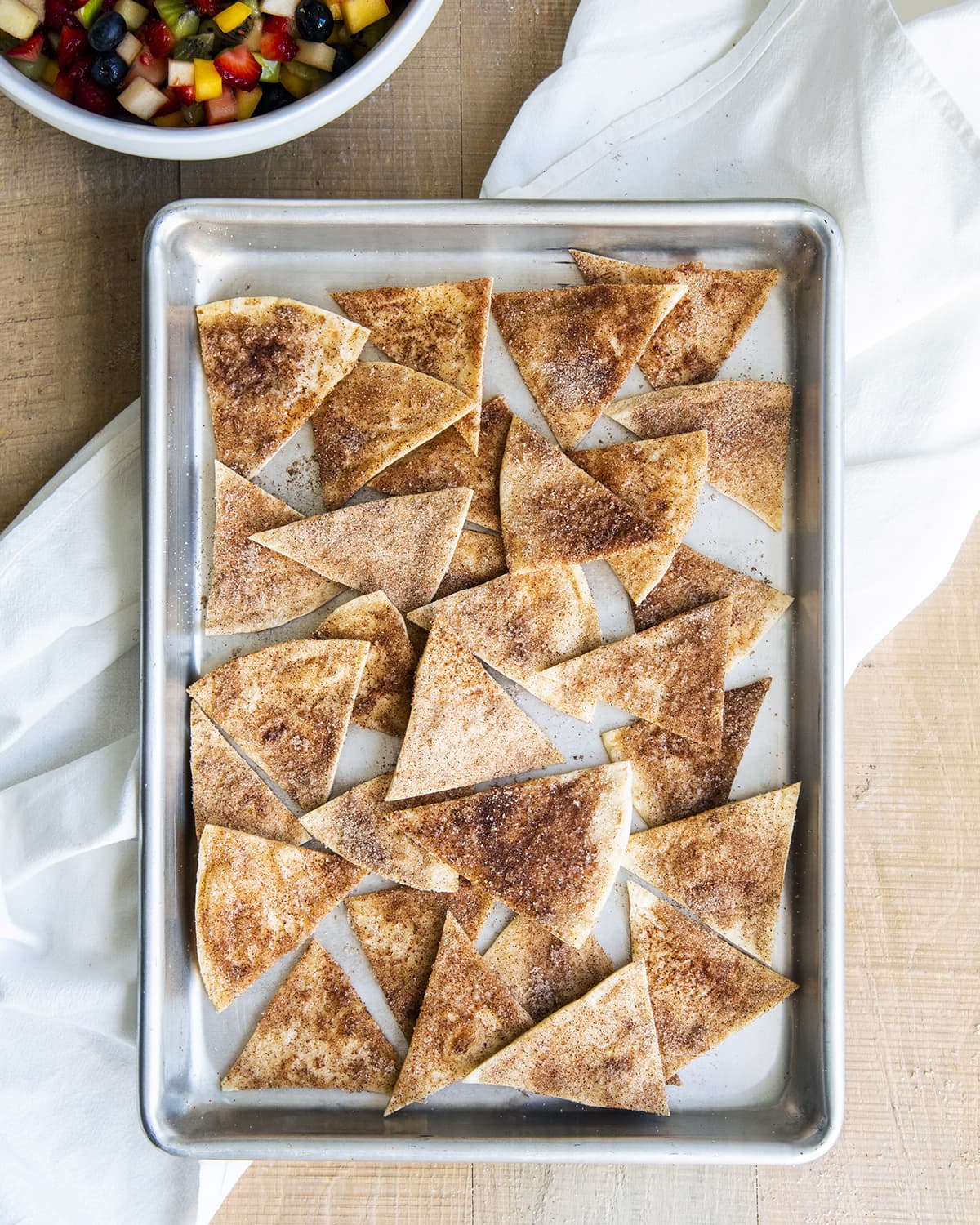 An overhead photo of cinnamon tortilla chips on a baking pan.