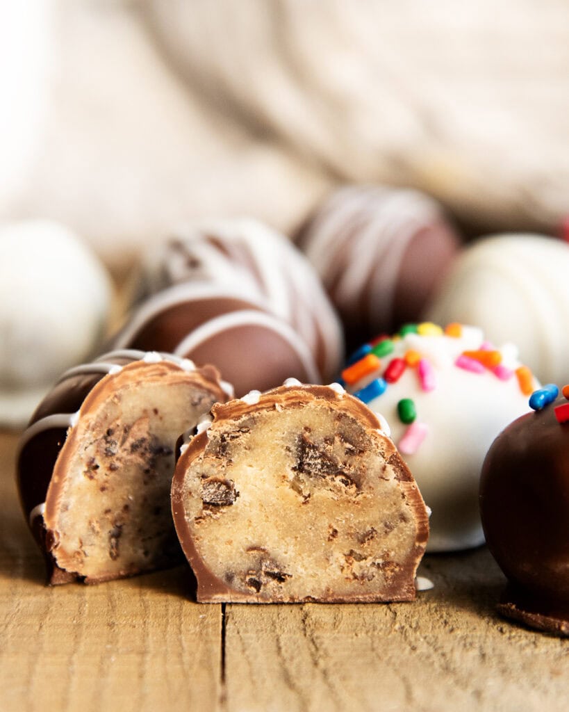 Two halves of a chocolate chip cookie dough truffle dipped in white chocolate.