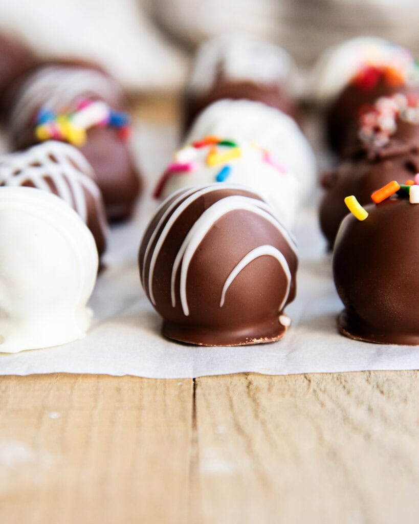 A truffle coated in chocolate, and drizzled with white chocolate.
