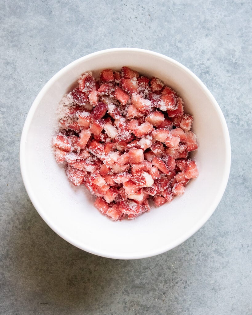 A bowl of chopped strawberries in sugar.