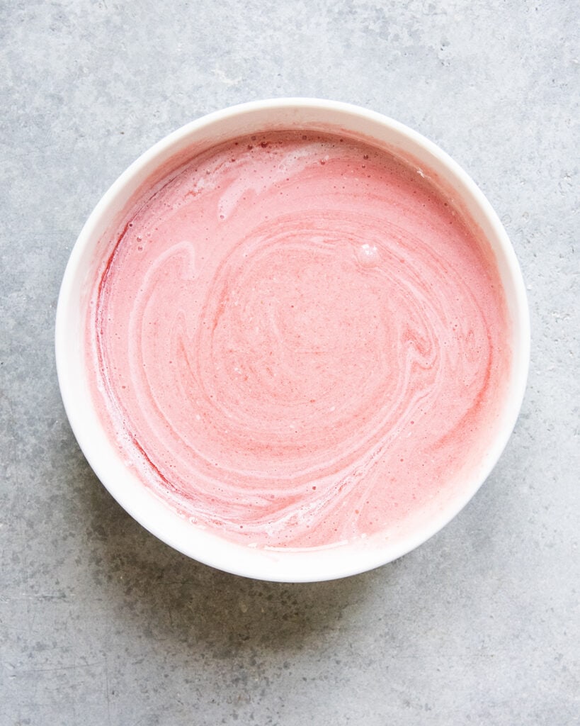 A bowl of strawberry puree mixed with half and half.