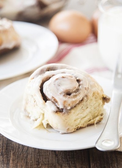Front view of cinnamon rolls on a white plate with a fork.