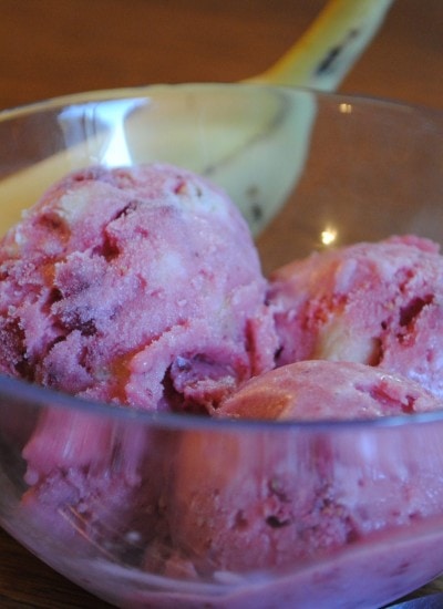 Angled view of strawberry banana sherbet in a glass bowl.