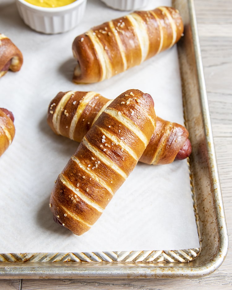 Pretzel hot dogs on a baking sheet.
