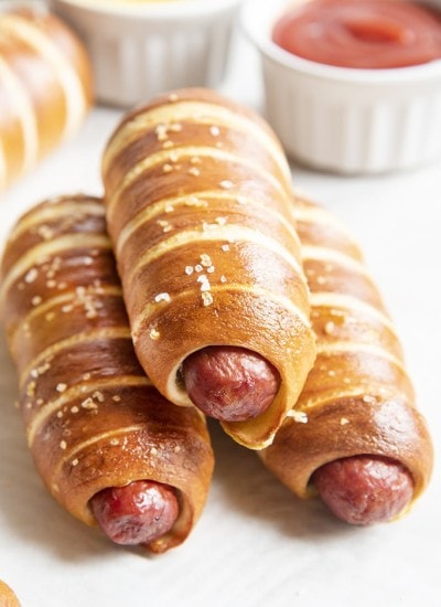 A stack of pretzel hot dogs with ketchup in the back