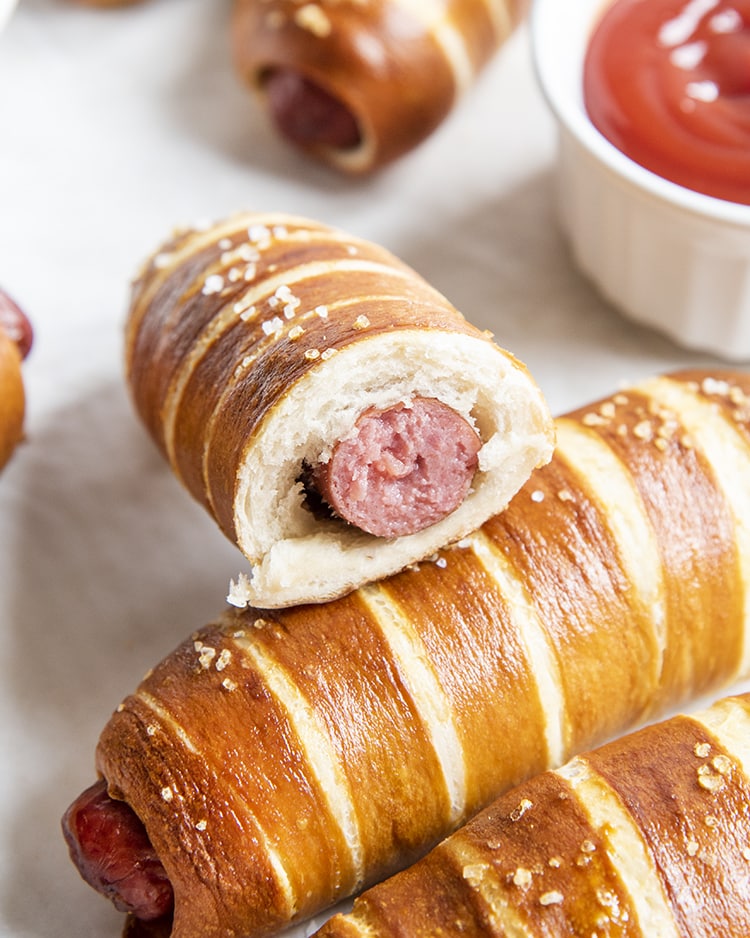 A hot dog wrapped in pretzel dough cut in half to show the inside