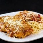 Angled view of eggplant parmesan on a plate with noodles.