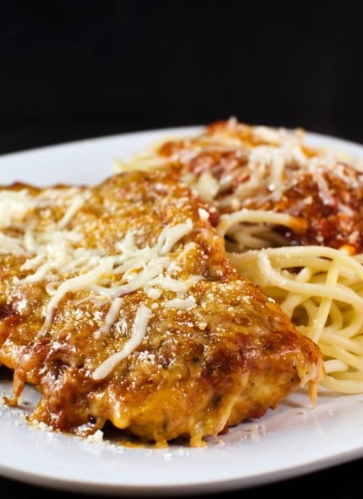 Angled view of eggplant parmesan on a plate with noodles.