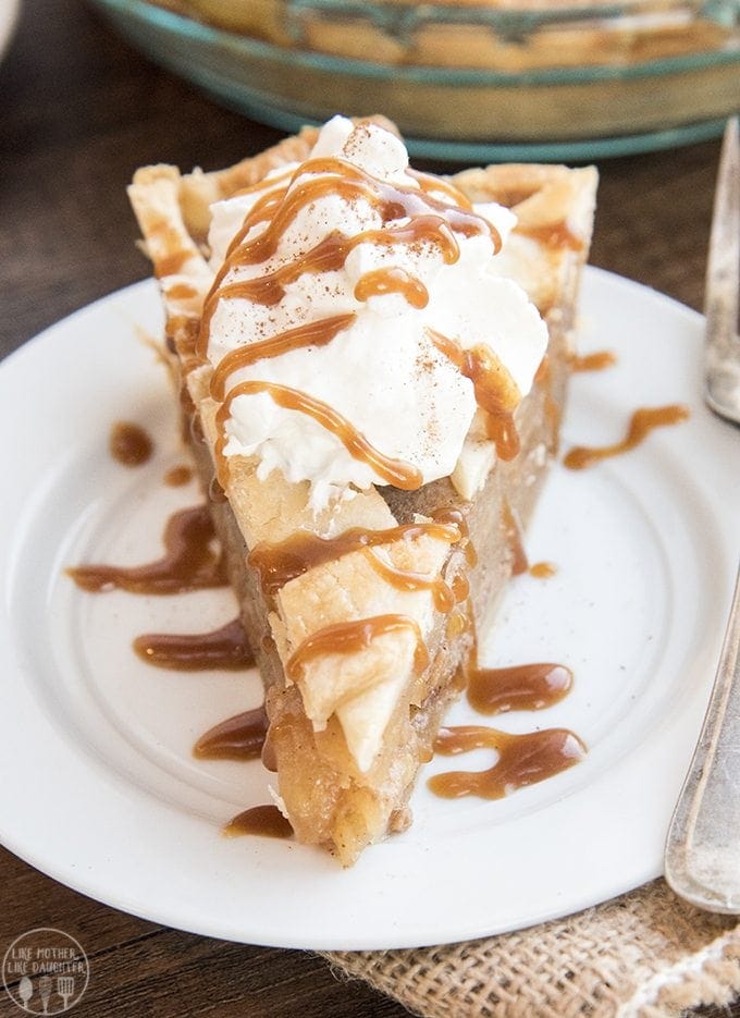 A piece of caramel apple pie topped with whipped cream and caramel sauce.