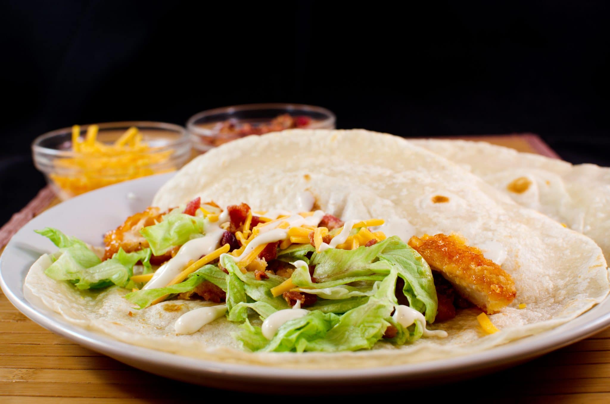 Side view of buffalo ranch chicken tacos on a white plate.