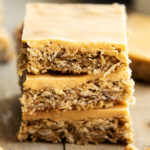 A close up of a stack of butterscotch bars on a wooden table.