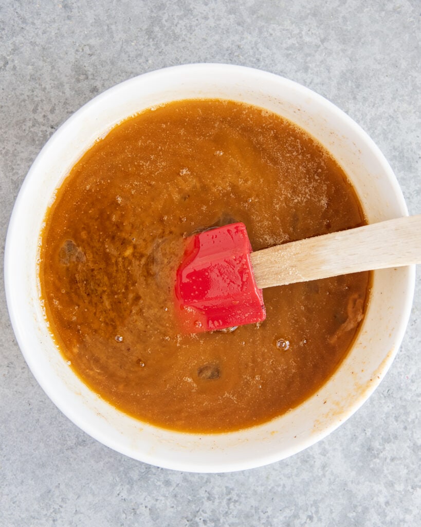 A bowl of melted, wet ingredients with an orange brown color.