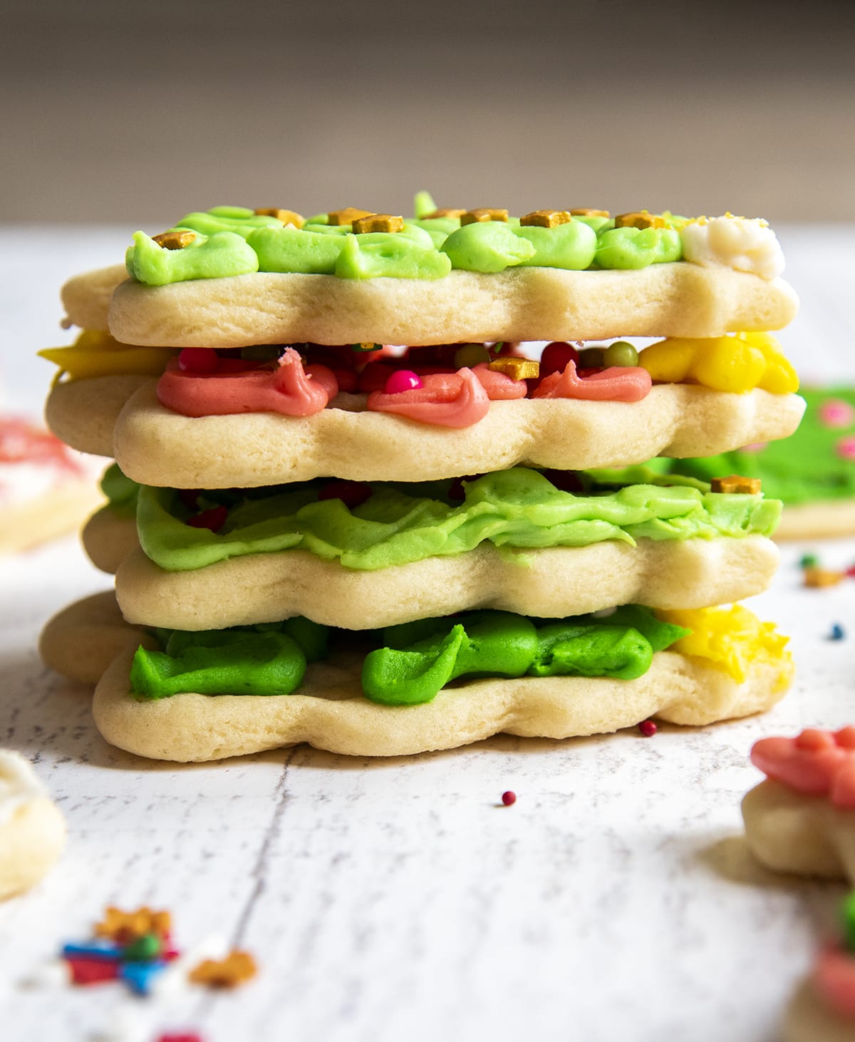 A stack of 4 Christmas tree sugar cookies showing the thick cookie and frosting on top.