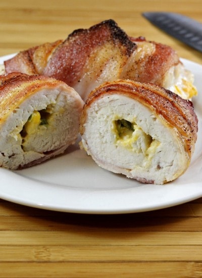 Front view of bacon wrapped jalapeno stuffed chicken breasts on a white plate.