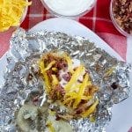 Top view of bbq chicken topped baked potato on foil.