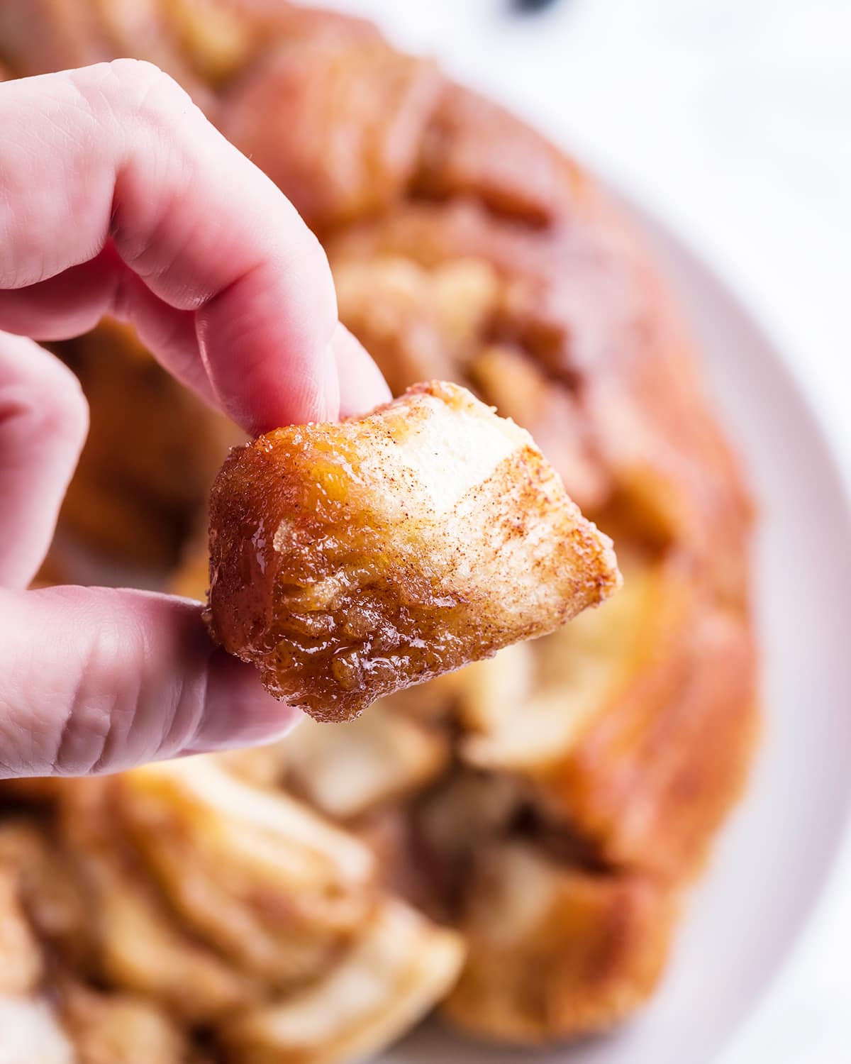 A hand holding a piece of monkey bread above the whole thing.