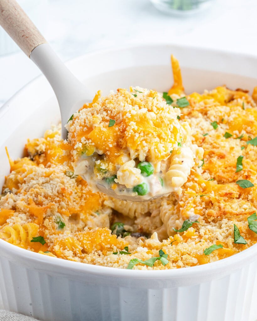 A scoop of cheesy noodle casserole full of peas, and a creamy sauce. 