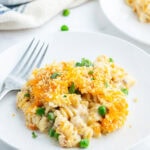 A plate of tuna casserole that is full of rotini pasta topped with melted cheese and bread crumbs.