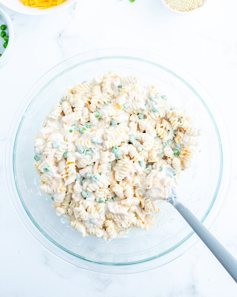 A bowl of pasta and peas coated in a creamy white sauce.