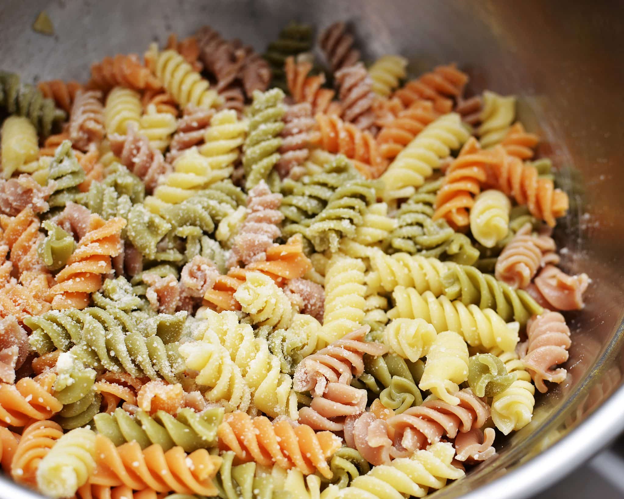 Close up view of pasta salad in a metal bowl.
