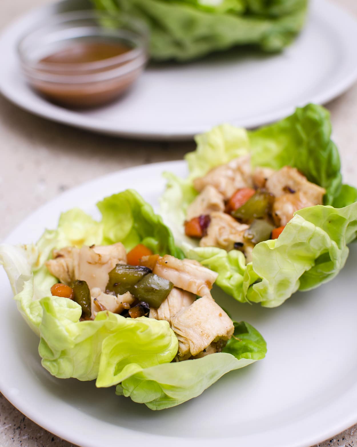 Close up view of chicken lettuce wraps on a white plate.