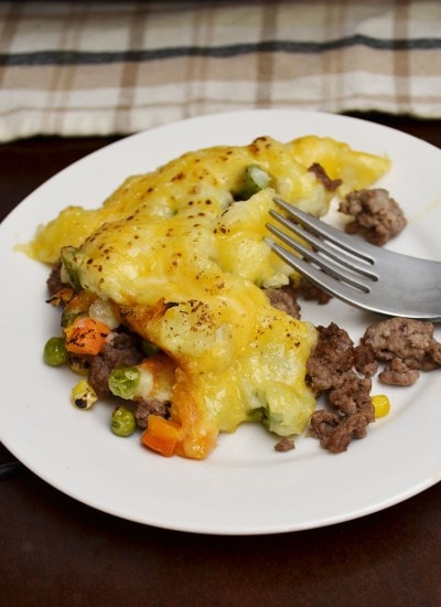Angled view of shepherds pie on a white plate with a fork.