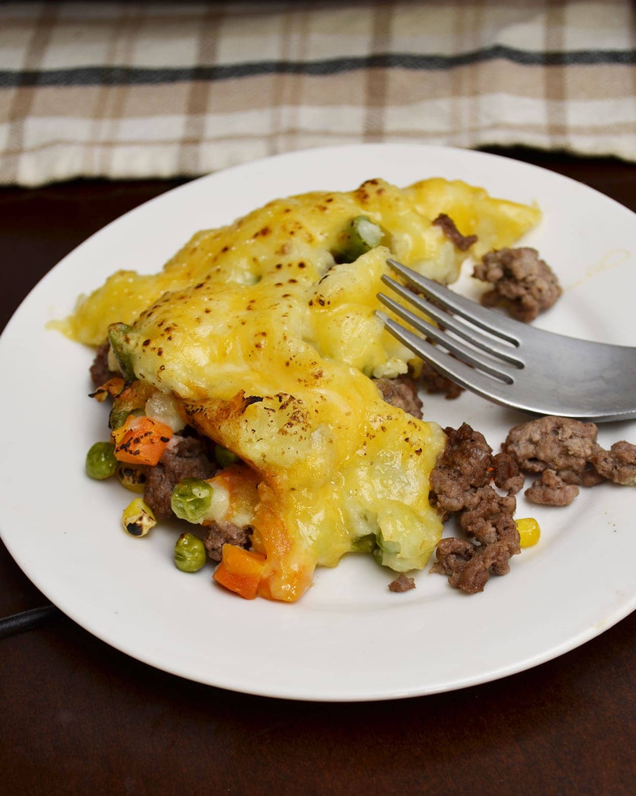 Angled view of shepherds pie on a white plate with a fork.
