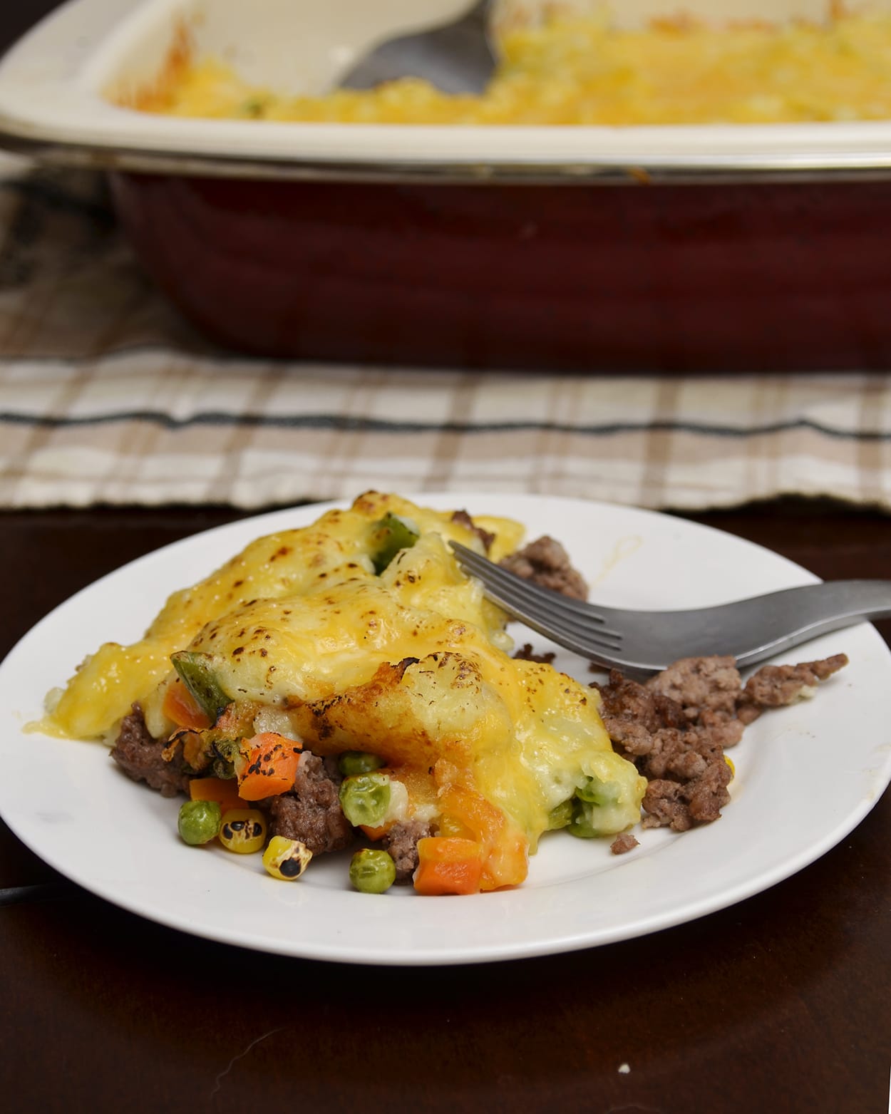 Front view of shepherds pie on a white plate with a fork.