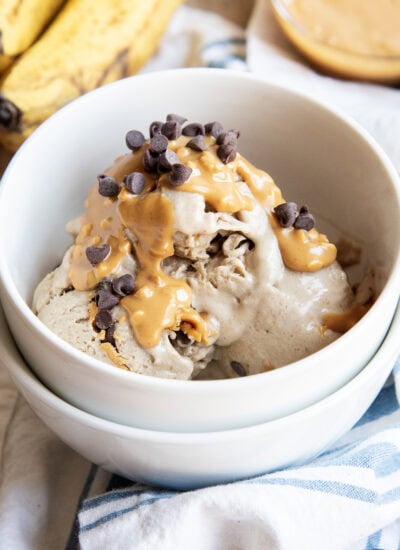 A bowl of healthy banana ice cream topped with peanut butter and mini chocolate chips.