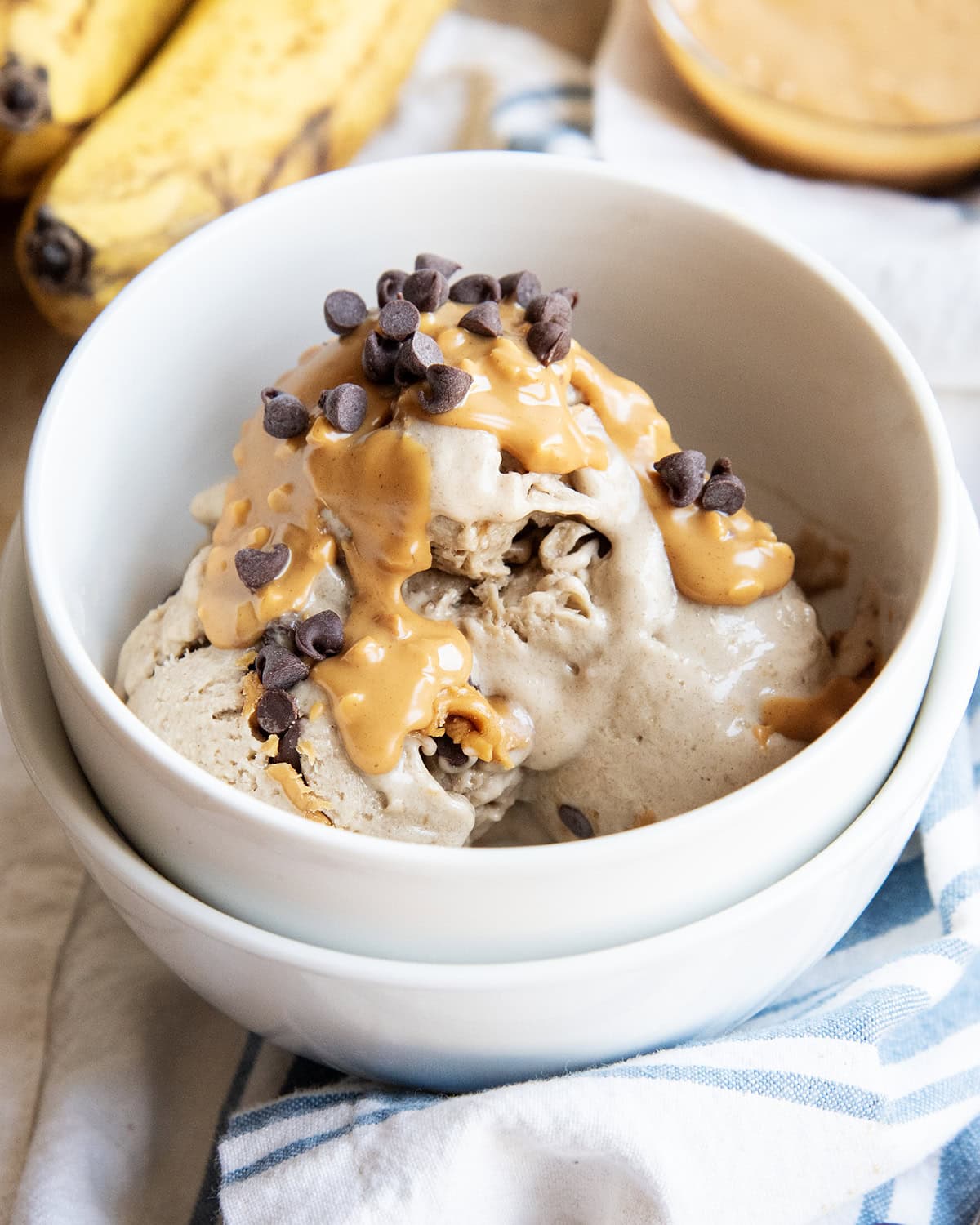A bowl of healthy banana ice cream topped with peanut butter and mini chocolate chips.