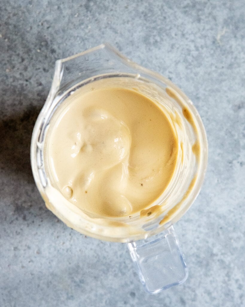 A blender with blended frozen bananas and peanut butter.