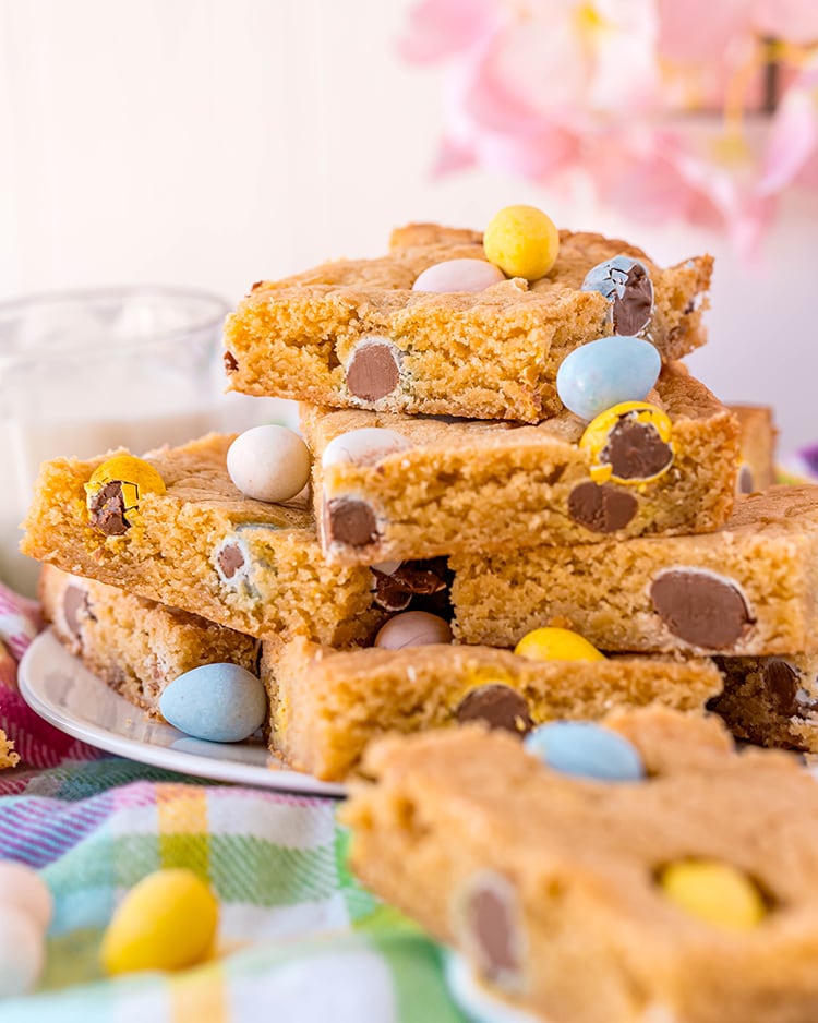 A plate of cookie bars full of cadbury mini eggs stacked in a pile.