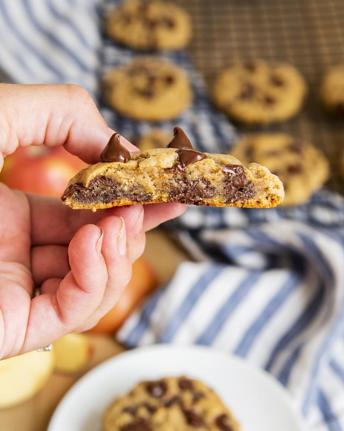 A hand holding half an applesauce chocolate chip cookie, showing the middle of the gooey cookie.