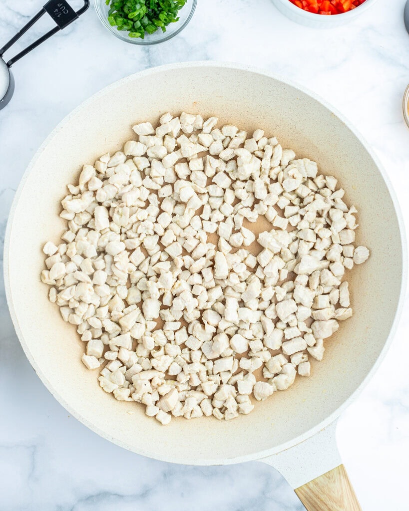 Small pieces of cooked chicken in a skillet.
